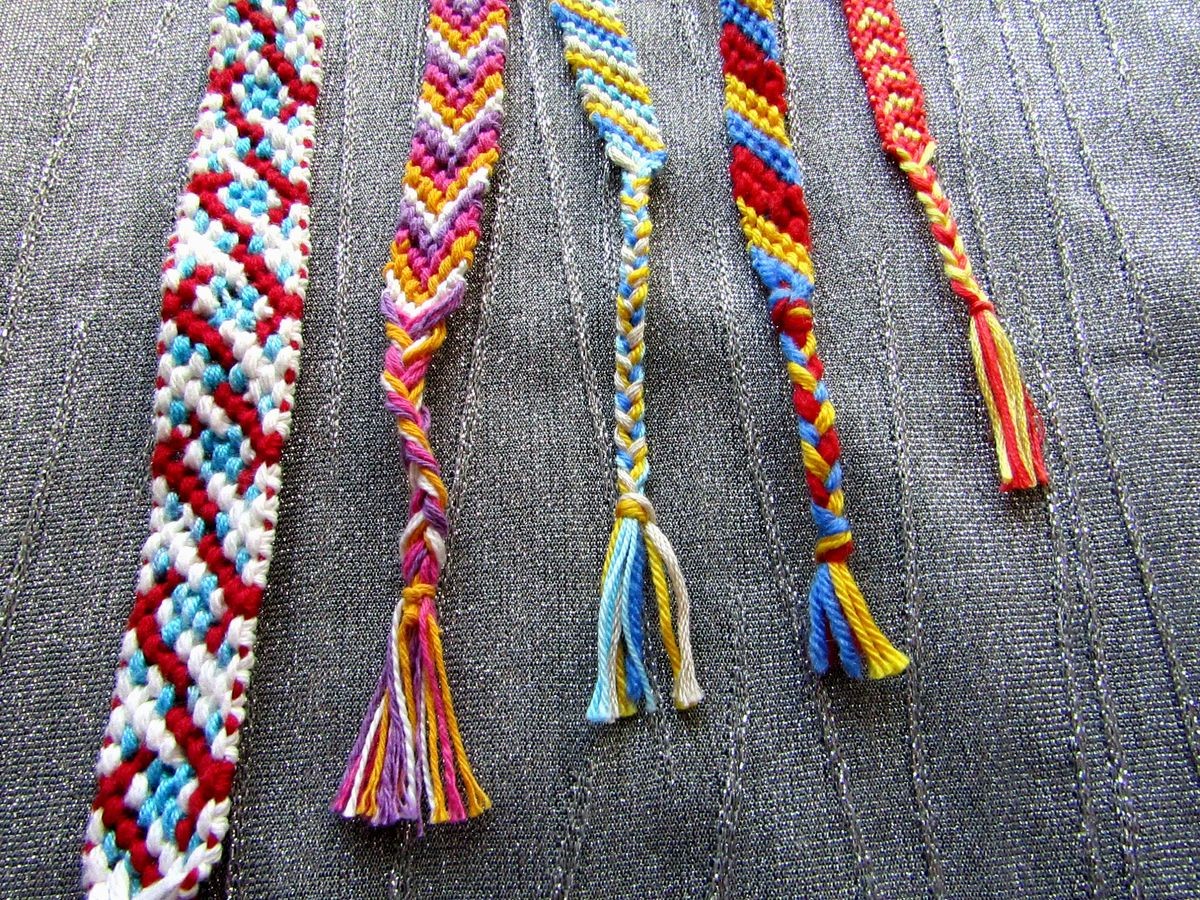 Woven friendship bracelets of threads with tassels on a gray background